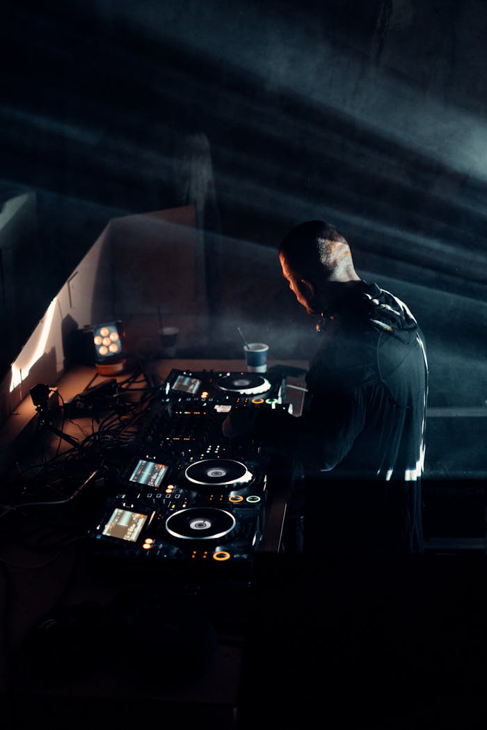 DJ mixing tracks at a dimly lit venue with advanced sound mixer equipment.